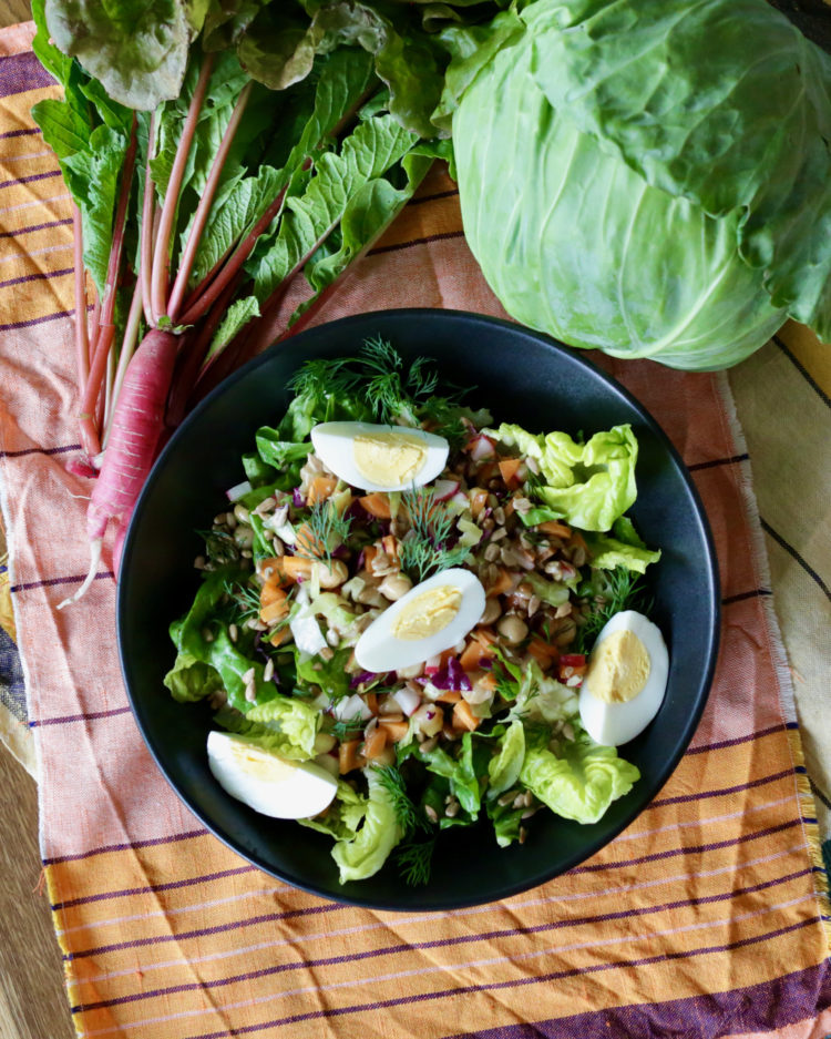 Breakfast salad with lettuce, cabbage, herbs, boiled egg, sunflower seeds and a quick simple vinaigrette