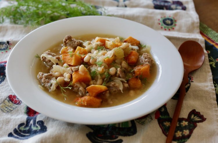 Bratwurst stew with navy beans and roasted butternut squash garnished with fresh dill