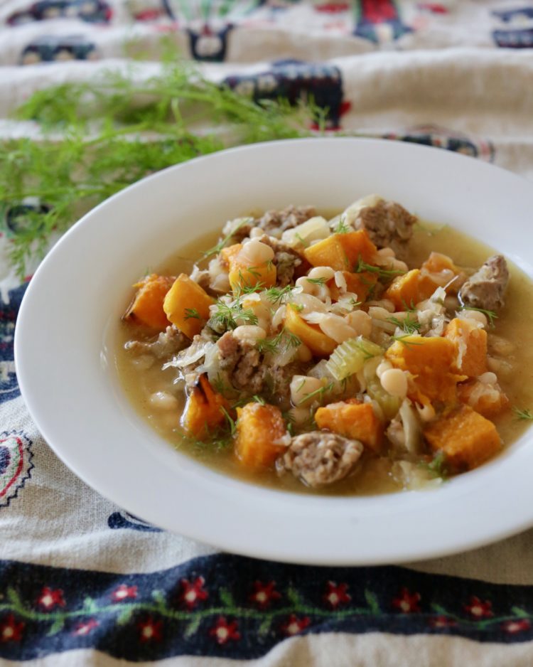 Bratwurst stew with navy beans and roasted butternut squash garnished with fresh dill