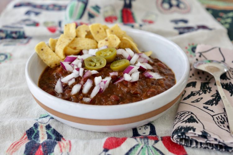 Bowl of vegan Frito pie with onions and jalapeños 