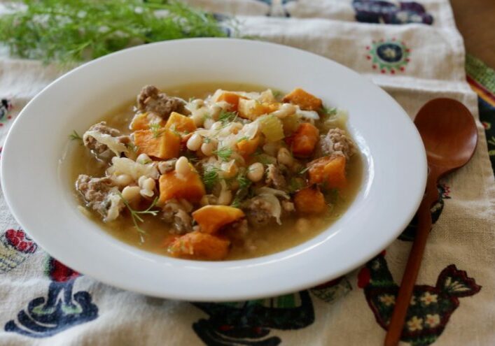 Bratwurst stew with navy beans and roasted butternut squash garnished with fresh dill